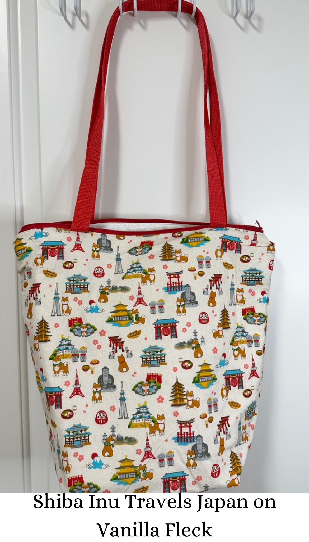 This tote has red handles and zipper. The motif is a cartoon styled Shiba Inu exploring Japan and seeing various icons like the Tokyo Tower, Sky Tree, Osaka Castle, Kinkakuji, Sensoji, and the gate at Miyajima. The background is an off-white with tiny brown speckles (reminds me of vanilla ice cream).
