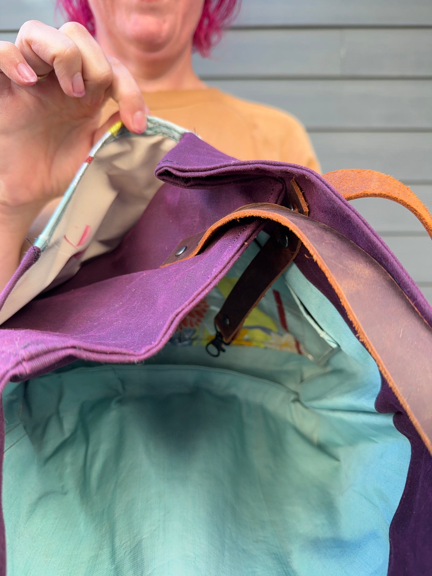 Woman holding a purple bag with a colourful interior; showing off external slip pocket lining, which is rose patterned haori.