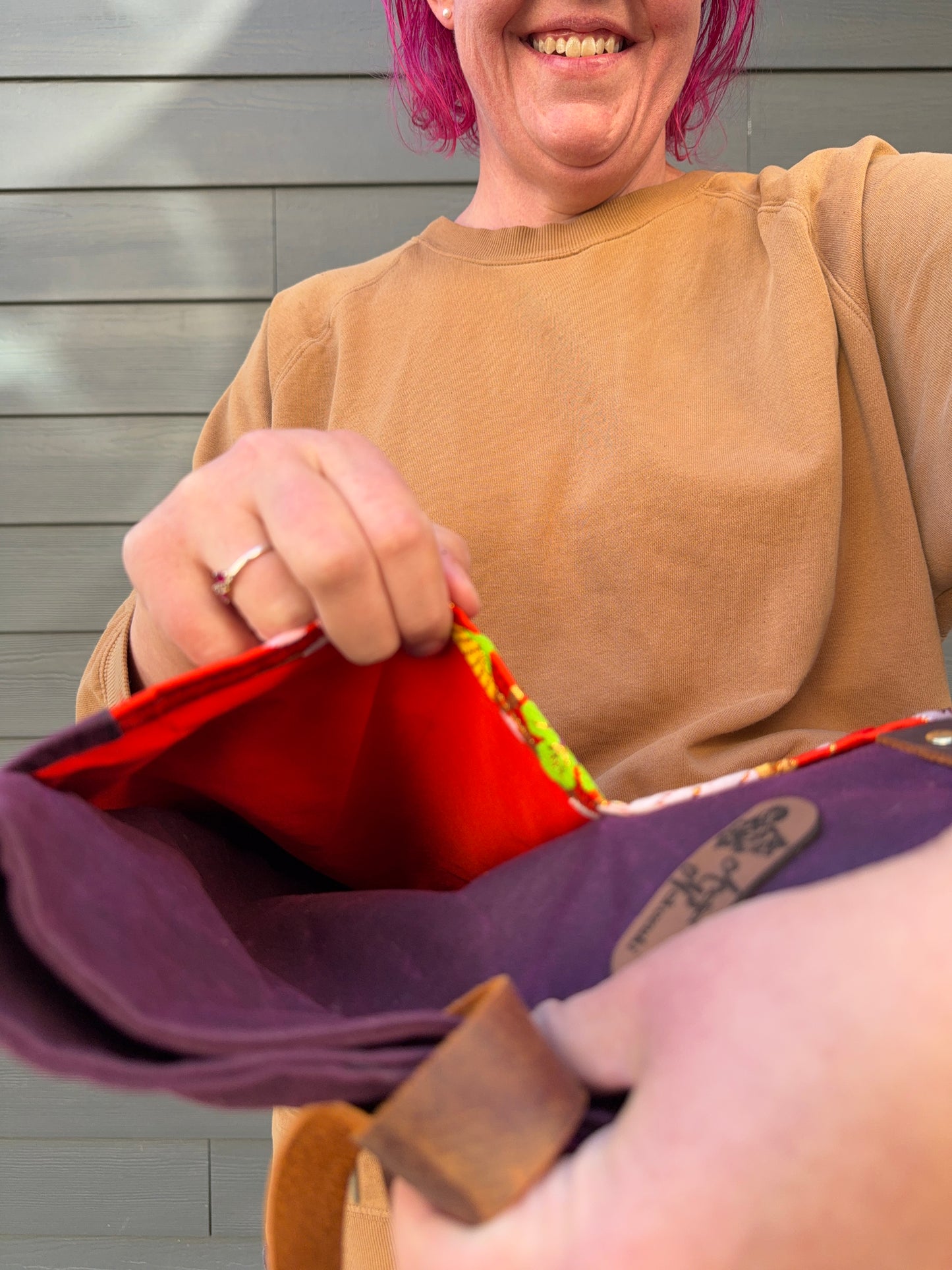 Person holding crane Dundurn Tote, showing off the orange lining for front pocket linings, all against a neutral background